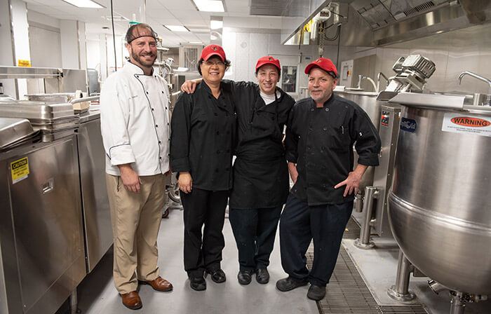 Employees in kitchen posing for the photo.